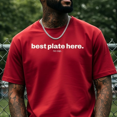 A man wearing a red crewneck t-shirt with white text that reads 'best plate here.' and 'no cap'.