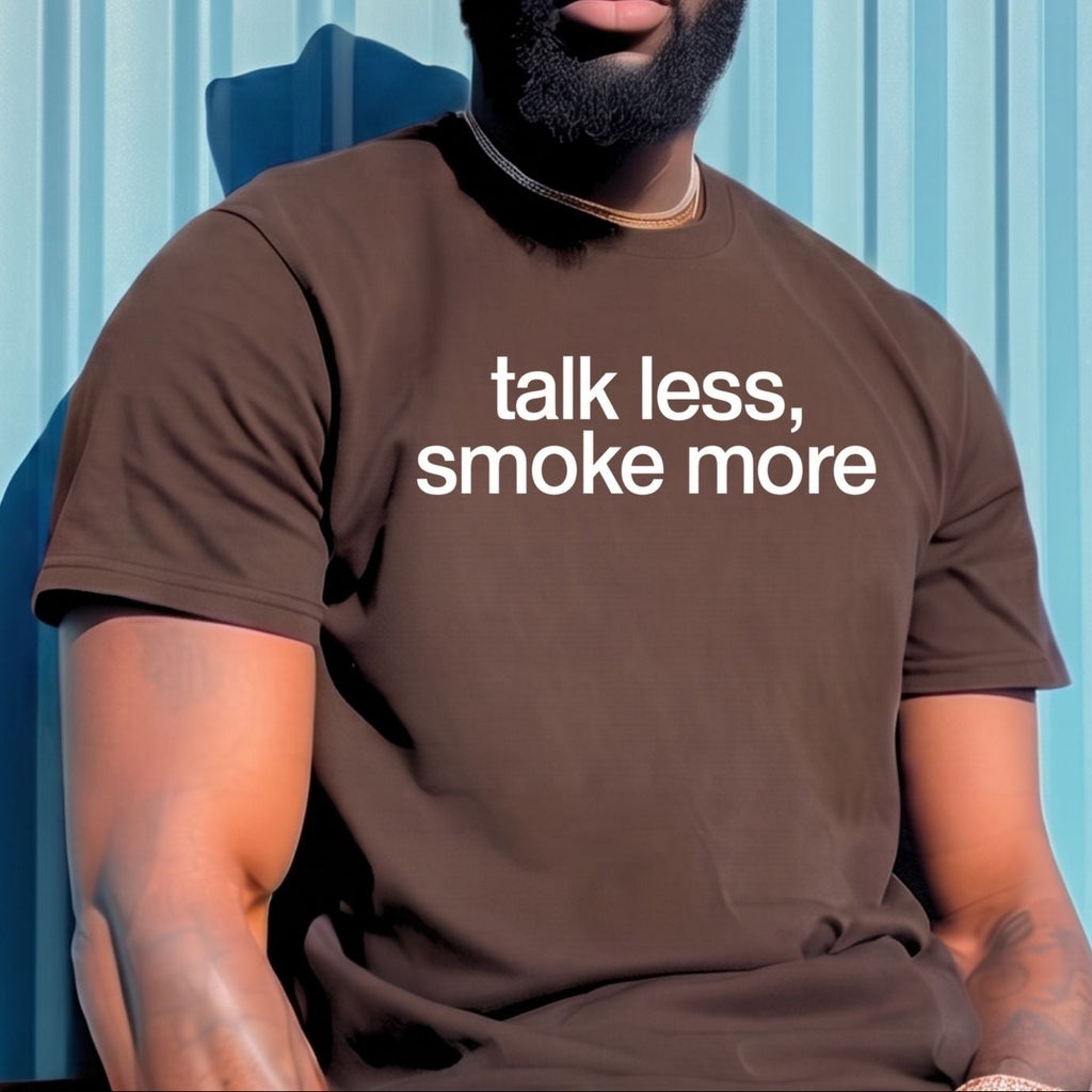 A man wearing a brown bucket hat, sunglasses, and a brown t-shirt with the white printed text 'talk less, smoke more' leans against a light blue corrugated metal wall.